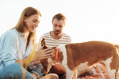 Sahada köpekli mutlu bir çiftin fotoğrafı.