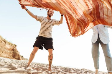 Kumsalda battaniyeli genç bir çiftin görüntüsü.