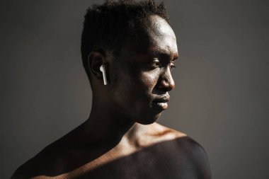 Genç Afro-Amerikan sporcusu gri arka planda tek başına çalışırken kulaklık kullanıyor.