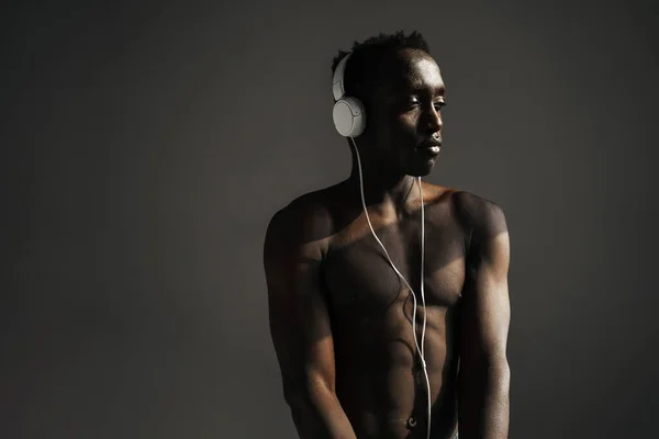 Ημιγυμνός Αφροαμερικάνος Αθλητής Που Χρησιμοποιεί Ακουστικά Ενώ Γυμνάζεται Απομονωμένος Γκρι — Φωτογραφία Αρχείου