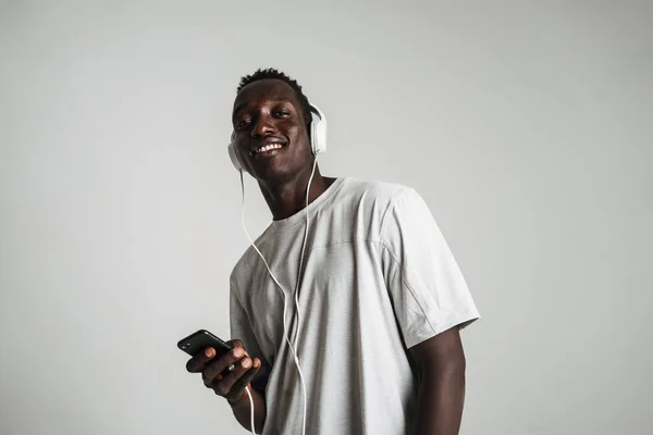 Счастливый Африканский Американец Слушает Музыку Наушниками Сотовым Телефоном Изолированы Белом — стоковое фото