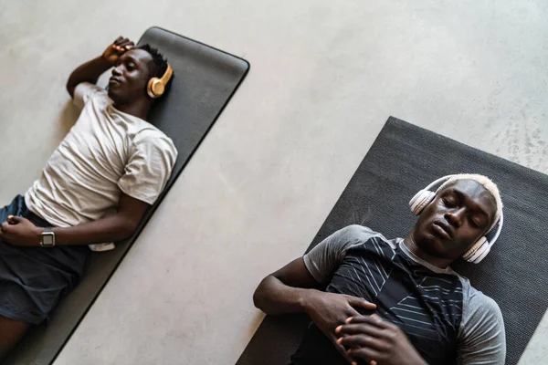 Два Молодых Атлетических Африканских Американца Наушниках Лежащих Коврике После Тренировки — стоковое фото