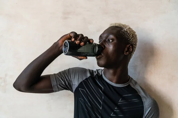 Молодой Атлетичный Красивый Африканский Американец Пьет Воду Стоя Стеной — стоковое фото