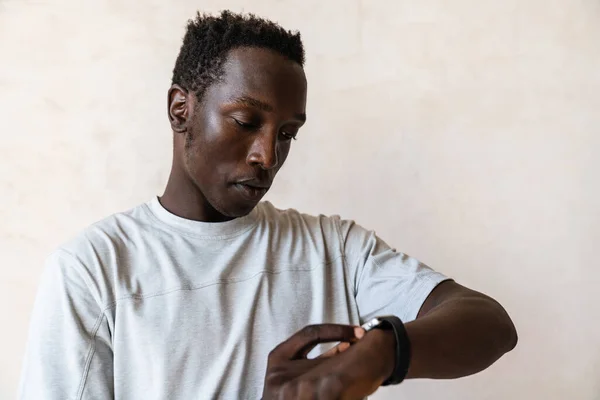 Молодой Серьезный Африканский Американец Смотрит Свои Наручные Часы Стоя Над — стоковое фото
