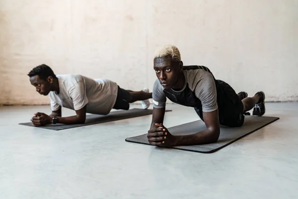 2人の若いハンサムなアフリカ系アメリカ人男性彼らの体を伸ばしながら屋内でワークアウト — ストック写真