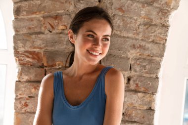 Genç mutlu esmer kadın gülümsüyor ve içeri bakıyor.