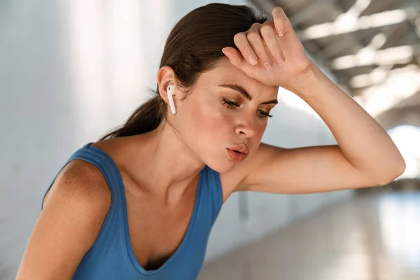 Krásná Unavená Sportovkyně Sluchátkách Odpočívající Při Cvičení Uvnitř — Stock fotografie