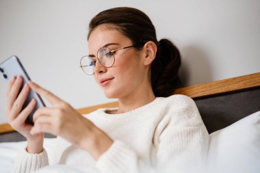 Evde kötü otururken cep telefonu kullanan güzel bir kız.