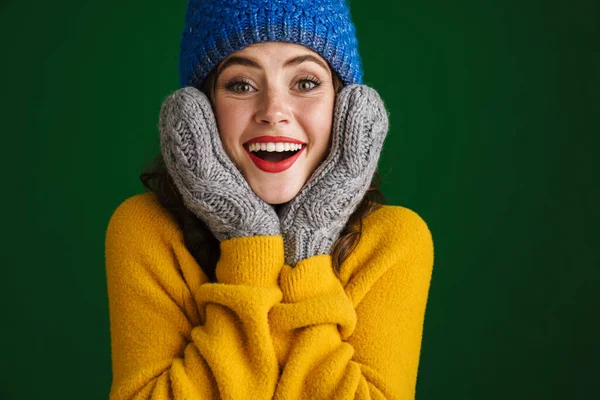 陽気美しいです若いです女性でセーターと帽子立って隔離された緑の背景 ミトンでポーズ — ストック写真