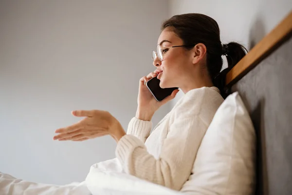 Beautiful Joyful Girl Talking Cell Phone While Sitting Bad Home — стоковое фото