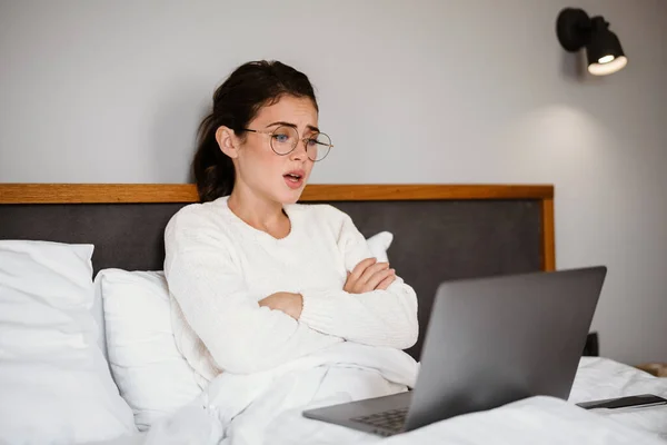 Menina Morena Infeliz Usando Laptop Enquanto Sentado Com Braços Cruzados — Fotografia de Stock