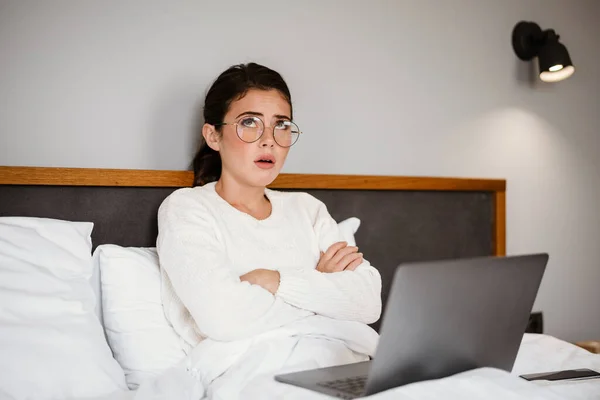 Menina Morena Infeliz Usando Laptop Enquanto Sentado Com Braços Cruzados — Fotografia de Stock