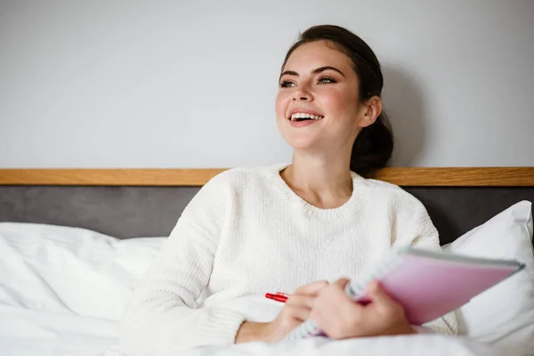 Encantadora Chica Alegre Sonriendo Anotando Notas Mientras Está Sentada Casa —  Fotos de Stock