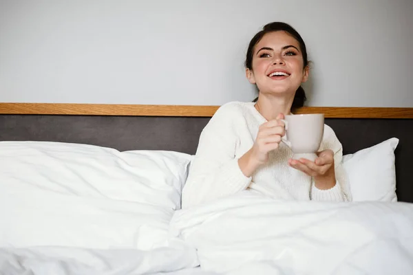 Charming Cheerful Girl Smiling Drinking Coffee While Sitting Bad Home — Stock Photo, Image