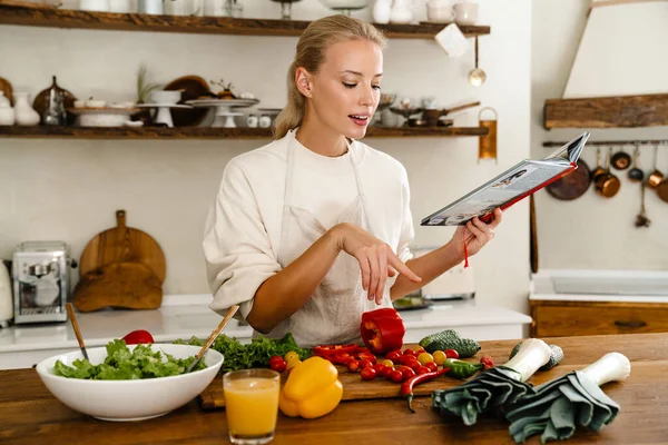 Güzel Düşünen Kadın Yemek Kitabı Okurken Sıcak Mutfakta Yemek Yapıyor — Stok fotoğraf