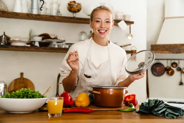 Güzel Mutlu Bir Kadın Sıcak Mutfakta Yemek Pişirirken Gülümsüyor — Stok fotoğraf