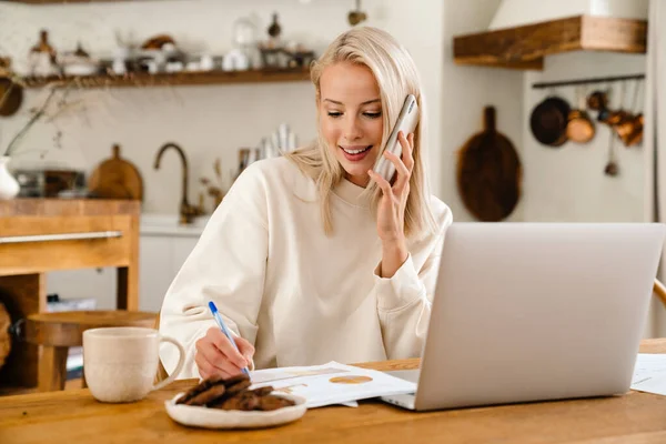 Hermosa Mujer Feliz Hablando Teléfono Inteligente Mientras Trabaja Con Ordenador — Foto de Stock
