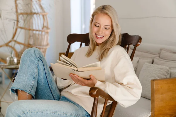 Hermosa Mujer Feliz Sonriendo Leyendo Libro Mientras Está Sentado Sillón — Foto de Stock