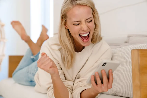 Nice Vzrušená Žena Dělat Vítězný Gesto Pomocí Mobilu Zatímco Leží — Stock fotografie