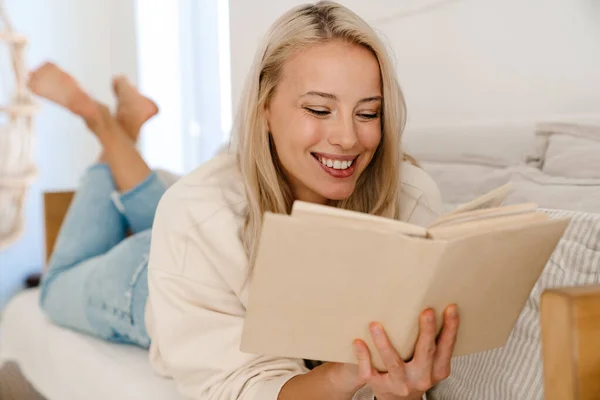 Hermosa Mujer Alegre Sonriendo Leyendo Libro Mientras Está Acostado Sofá — Foto de Stock