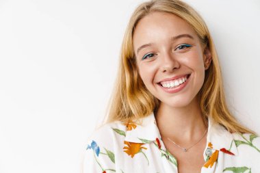 Mutlu güzel kız gülümsüyor ve beyaz arka planda izole edilmiş kameraya bakıyor.