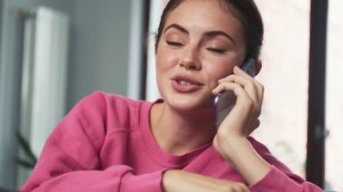 Evde cep telefonuyla konuşan mutlu iyimser genç kız.