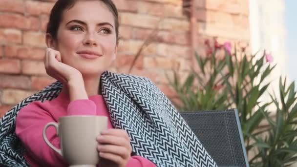 若いです陽気な女の子座って屋外でコーヒーを飲む — ストック動画