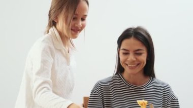 Genç ve mutlu bir kadın evde kızıyla kahvaltı yapıyor ve eğleniyor.