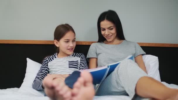 Joven Madre Positiva Haciendo Tarea Con Hija Casa Una Cama — Vídeos de Stock