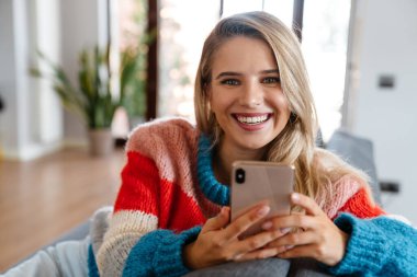 Çekici, gülümseyen, cep telefonu kullanan genç bir kadın.