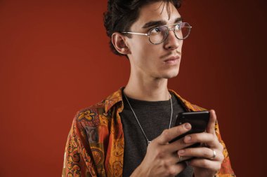 Düşünceli hippi, kırmızı arka planda izole bir şekilde internetten haberleri okuyor.