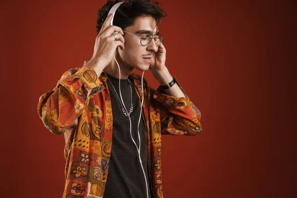 Mladý Muž Těší Hudbu Poslech Prostřednictvím Bezdrátových Sluchátek Izolovaných Červeném — Stock fotografie