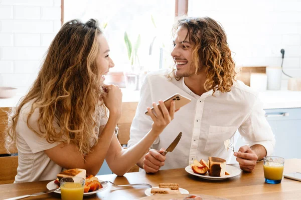 Happy Beautiful Couple Smiling Using Cellphone While Having Breakfast Cozy — Stock Photo, Image