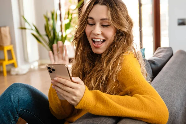 Menina Bonita Feliz Sorrindo Usando Celular Enquanto Descansa Sofá Casa — Fotografia de Stock