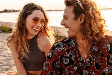 Sahilde birbirine bakan mutlu, pozitif, genç bir çiftin görüntüsü.