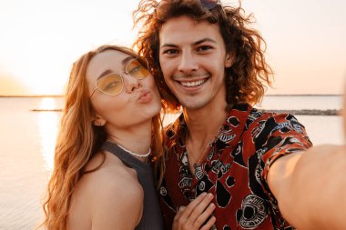 Sahilde fotoğraf çeken mutlu ve genç bir çiftin görüntüsü.