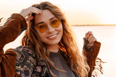 Sahilde yürüyen neşeli, genç bir kadının görüntüsü.