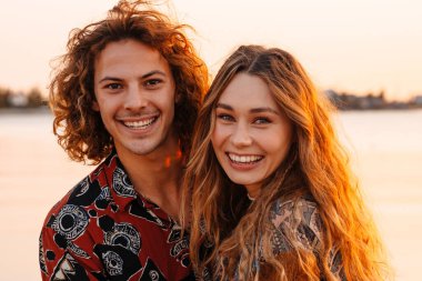 Sahilde mutlu, genç ve sevgi dolu bir çiftin fotoğrafı.