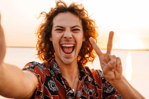 Szczęśliwy Młody Człowiek Robi Sobie Selfie Stojąc Plaży Zachodzie Słońca — Zdjęcie stockowe