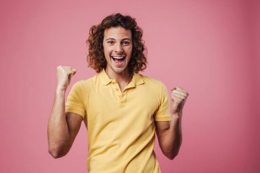 Excited handsome guy exclaiming and making winner gesture isolated over pink background clipart