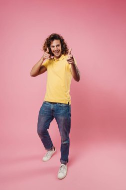 Mutlu beyaz adam gülümsüyor ve pembe arka planda izole edilmiş kamerayı işaret ediyor.