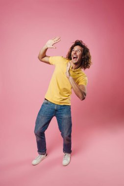 Neşeli, yakışıklı beyaz adam gülüyor ve pembe arka planda izole edilmiş dur hareketi gösteriyor.