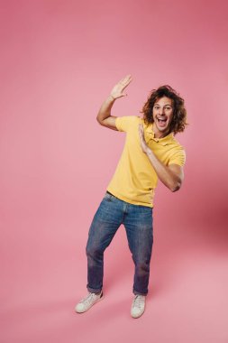 Neşeli, yakışıklı beyaz adam gülüyor ve pembe arka planda izole edilmiş dur hareketi gösteriyor.