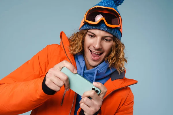 Hombre Vistiendo Chaqueta Invierno Celebración Teléfono Móvil Sobre Fondo Azul — Foto de Stock