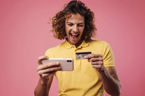 Glädjande Snygg Kille Poserar Med Kreditkort Och Mobiltelefon Isolerad Över — Stockfoto