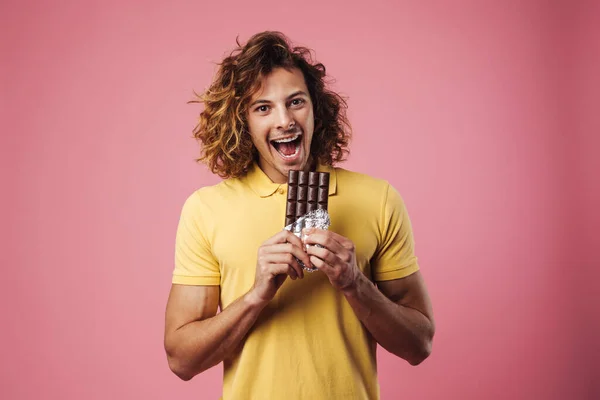 Veselý Hezký Chlap Usmívá Při Jídle Čokolády Izolované Přes Růžové — Stock fotografie