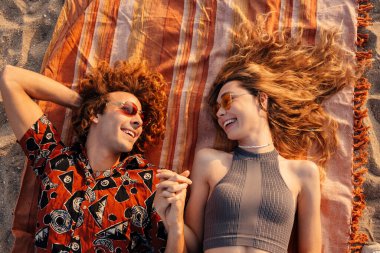 Sahilde yatan neşeli, genç bir çiftin görüntüsü.