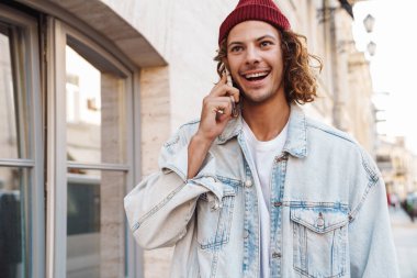 Pozitif kıvırcık bir adamın sokak sokak dolaşıp cep telefonuyla konuşması.