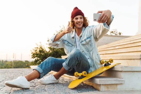 Obrázek Potěšeného Mladého Kudrnatého Muže Jak Sedí Venku Fotí Selfie — Stock fotografie