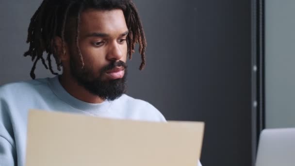 Ein Ernsthafter Junger Afrikanisch Amerikanischer Mann Arbeitet Mit Papierdokumenten Die — Stockvideo